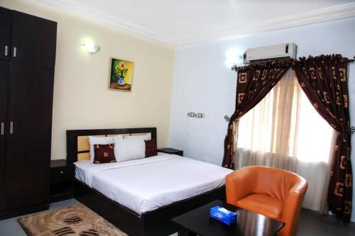 a bedroom with a bed and a chair and a window at Western Dreams Hotel in Abuja