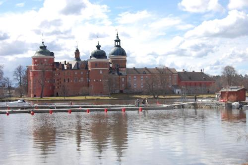 a large red brick building next to a body of water at Röda Magasinet in Mariefred