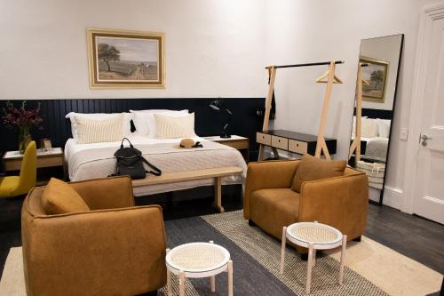 een slaapkamer met een bed, 2 stoelen en een spiegel bij Heritage House in Stellenbosch