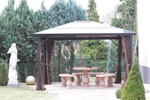 a gazebo with a table and benches in a garden at Naam Hotel & Apartments Frankfurt City-Messe Airport in Frankfurt