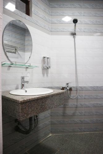 a bathroom with a sink and a shower with a mirror at Anh Quân Hotel in Quy Nhon