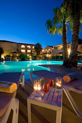 a swimming pool with a table and candles in front of it at Le Cottage - Hotel & Spa in Argelès-sur-Mer