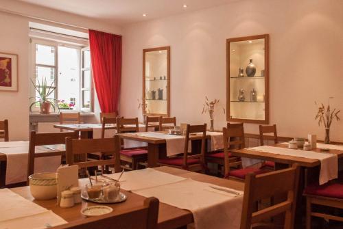 Hotel Seethaler في شتراوبينج: مطعم بطاولات وكراسي ومرآة