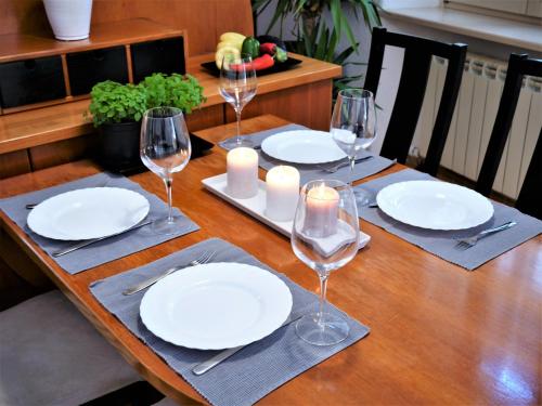 a wooden table with white plates and wine glasses at 3PAPIGE Apartment in Piran