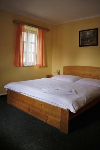 a bedroom with a large wooden bed with white sheets at Penzion U Studeného potoka in Nové Hutě