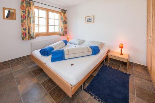 een slaapkamer met een groot bed met blauwe kussens bij Försterli West in Grächen