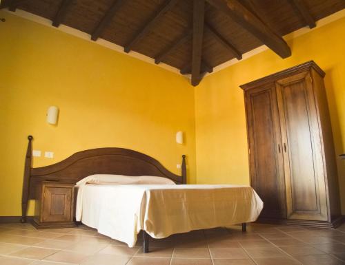 a bedroom with a bed in a yellow wall at Tenuta Su Vrau in Posada