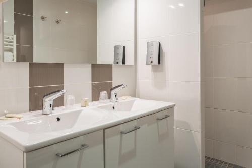 W białej łazience znajduje się umywalka i lustro. w obiekcie Hotel Restaurant LE YETI ancien Gai pinson w mieście Les Rousses