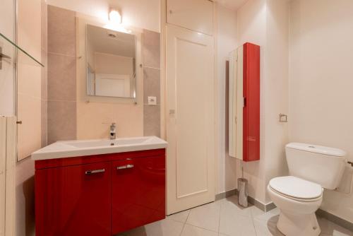 La salle de bains est pourvue d'un lavabo rouge et de toilettes. dans l'établissement Le Bord de Garonne, à Toulouse