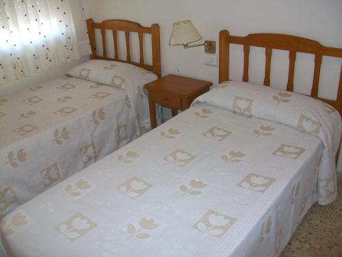 two beds in a small room with two tables at Infante - Primera Línea de Playa in Playa de Gandia