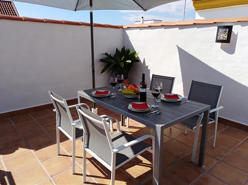 einen Esstisch mit Stühlen und einem Sonnenschirm auf einer Terrasse in der Unterkunft Alzahira 1 in Córdoba