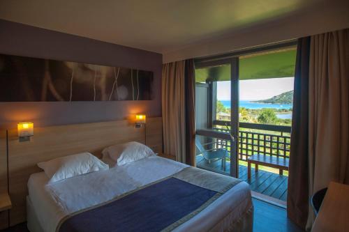 a hotel room with a bed and a view of the ocean at Hôtel Castell'Verde in Porto-Vecchio