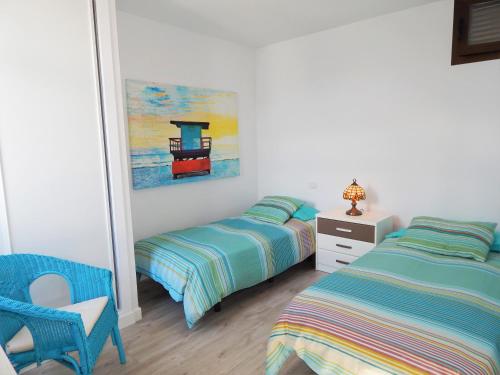 プラヤ・デ・ラス・アメリカスにあるTroya Beachのベッドルーム1室(ベッド2台、椅子、絵画付)