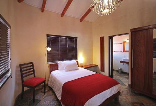 a bedroom with a bed and a chair and a chandelier at Hartmann Suites Serviced Self-Catering Apartments in Windhoek