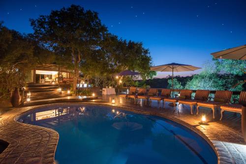 a swimming pool with chairs and a patio at night at Waterbuck Game Lodge Thornybush Nature Reserve in Thornybush Game Reserve