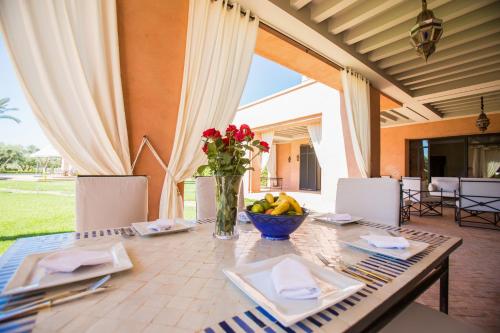 a table with a vase of flowers and a bowl of fruit at Villa Koutoubia, jardin luxuriant, piscine et spa in Marrakech