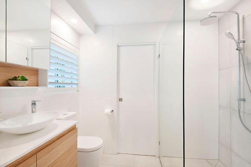 a white bathroom with a shower and a sink at Durramboi Luxury Apartment in Noosaville