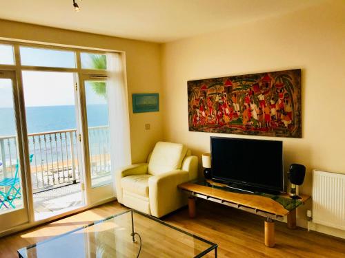 sala de estar con TV de pantalla plana y sofá en 'Kaia' Beach Vista, Ventnor Beach en Ventnor