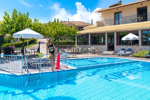 a woman is standing next to a swimming pool at Thermios Apollon in Thermo