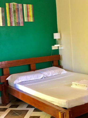 a bed in a room with a green wall at Chaniva-Joy Island View Appartments in Malapascua Island