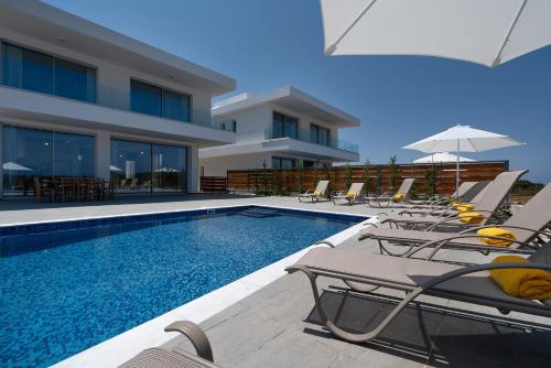 a swimming pool with chairs and an umbrella next to a building at Sea Point Villas in Coral Bay
