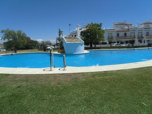 une grande piscine bleue en face d'un bâtiment dans l'établissement Apart Club la Barrosa, à Chiclana de la Frontera