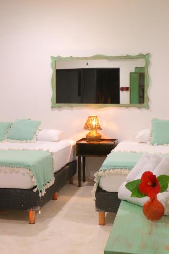 Habitación con 3 camas y espejo en la pared. en Punta Piedra Beach Posada, en Tulum
