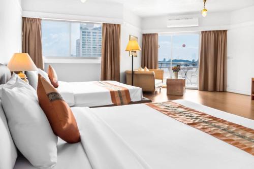 a hotel room with two beds and a living room at Markland Seaside Pattaya in Pattaya