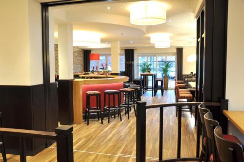 a bar in a restaurant with chairs and tables at Hotel Drei Linden in Twist