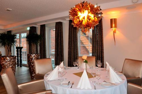 a dining room with a table and a chandelier at Hotel Drei Linden in Twist