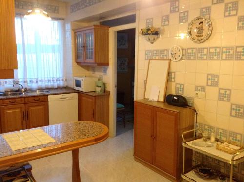 a kitchen with wooden cabinets and a table in it at APARTAMENTO 10 PISO VISTAS AL MAR in Ferrol