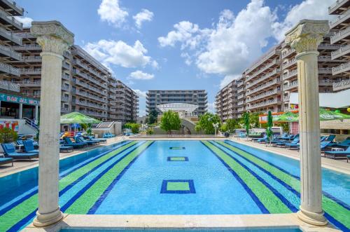 una grande piscina con sedie blu e edifici di Phoenicia Holiday Resort a Mamaia Nord - Năvodari