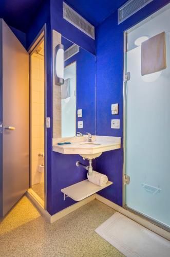 a blue bathroom with a sink and a mirror at ibis budget SP Centro Sao Joao in Sao Paulo