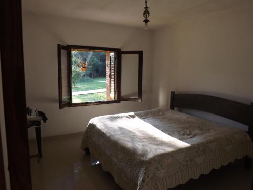 a bedroom with a bed and a window at Sitio do Tonetti in Mairiporã