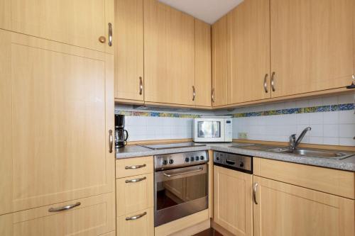 eine Küche mit Holzschränken und einer Mikrowelle in der Unterkunft Apartmenthaus Strelasund Whg  11 in Binz