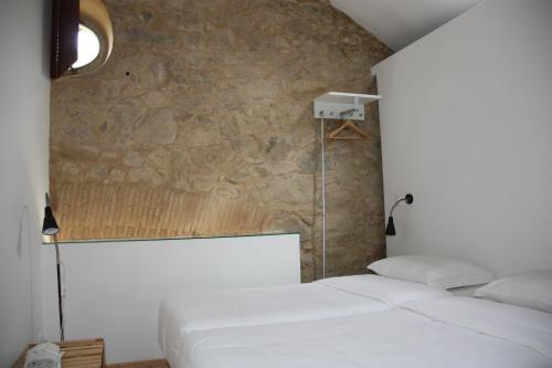 Casa de Campo Moinhos da Gozundeira في سوبرال دي مونتي أغراشو: سريرين بيض في غرفة بجدار حجري