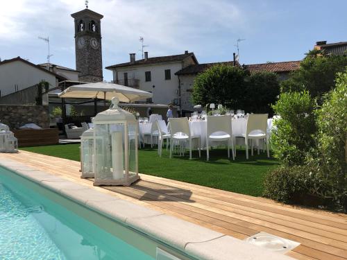 a pool with a table and chairs and a clock tower at La Locanda Del Grop in Tavagnacco