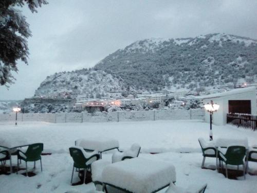 a table and chairs covered in snow with a mountain at Villa Turística de Grazalema in Grazalema