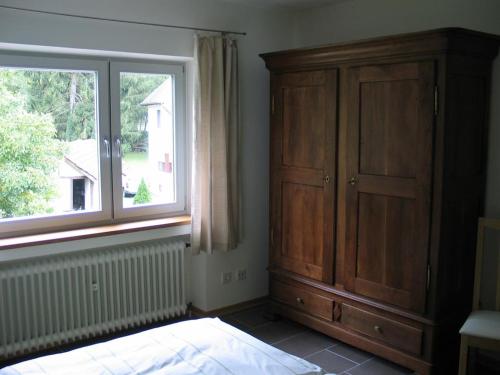 a bedroom with a wooden cabinet and a window at Irreler Mühle Ferienwohnungen und Ferienhäuser in Irrel