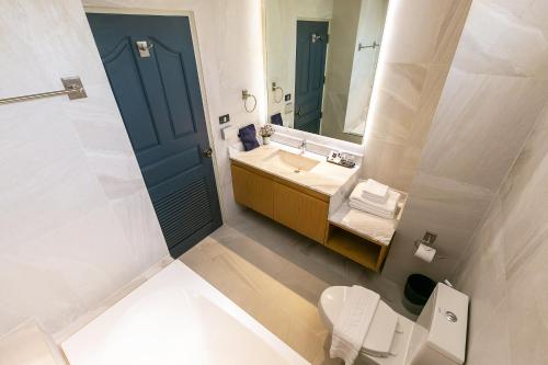 a bathroom with a sink and a toilet and a mirror at THEA Private Suites by TH District in Bangkok