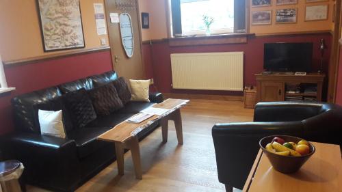 a living room with a black leather couch and a table at Leven and Linnhe Apartments, West Highland Way Holidays in Kinlochleven