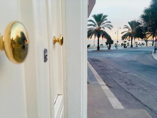 a door with a view of a street and palm trees at Domus Bianca Lancia in Manfredonia