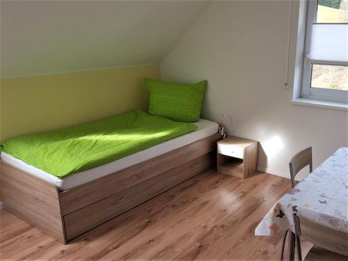 ein kleines Schlafzimmer mit einem Bett mit einem grünen Kissen in der Unterkunft Ferienwohnung am Bach in Unterkirnach