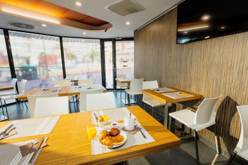 un restaurant avec des tables et des chaises et une assiette de nourriture dans l'établissement Appart-Hôtel Mer & Golf City Perpignan Centre, à Perpignan