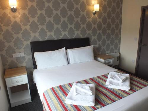a bedroom with a large bed with two towels on it at The Kingstanding Inn in Birmingham