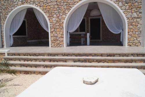 a table in front of a building with white curtains at STUDIOSWORX Apartments in Ios Chora