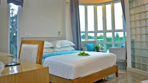 a bedroom with a bed and a desk and windows at Hotel Star Shell in Hulhumale