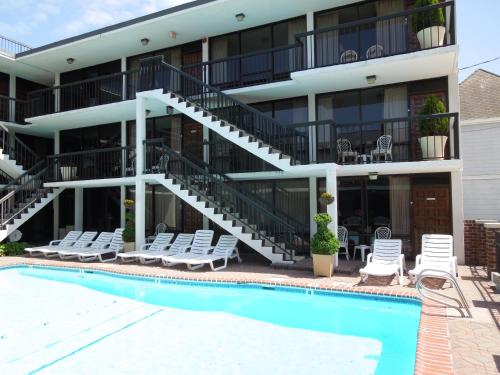 a hotel with a swimming pool and chairs and a building at Alamar Resort Inn in Virginia Beach