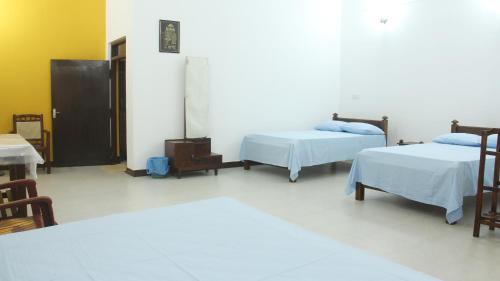a room with two beds and a table and chairs at Grand Villa in Anuradhapura