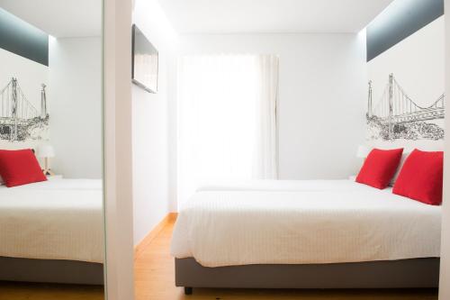 two beds in a room with red pillows at Páteo Saudade Lofts in Lisbon